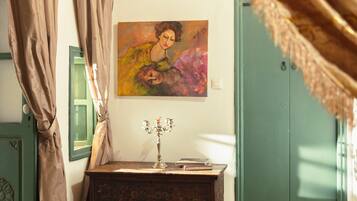 Une chambre à coucher avec un lit, une table de chevet surmontée d’un chandelier, un tableau et une armoire verte.