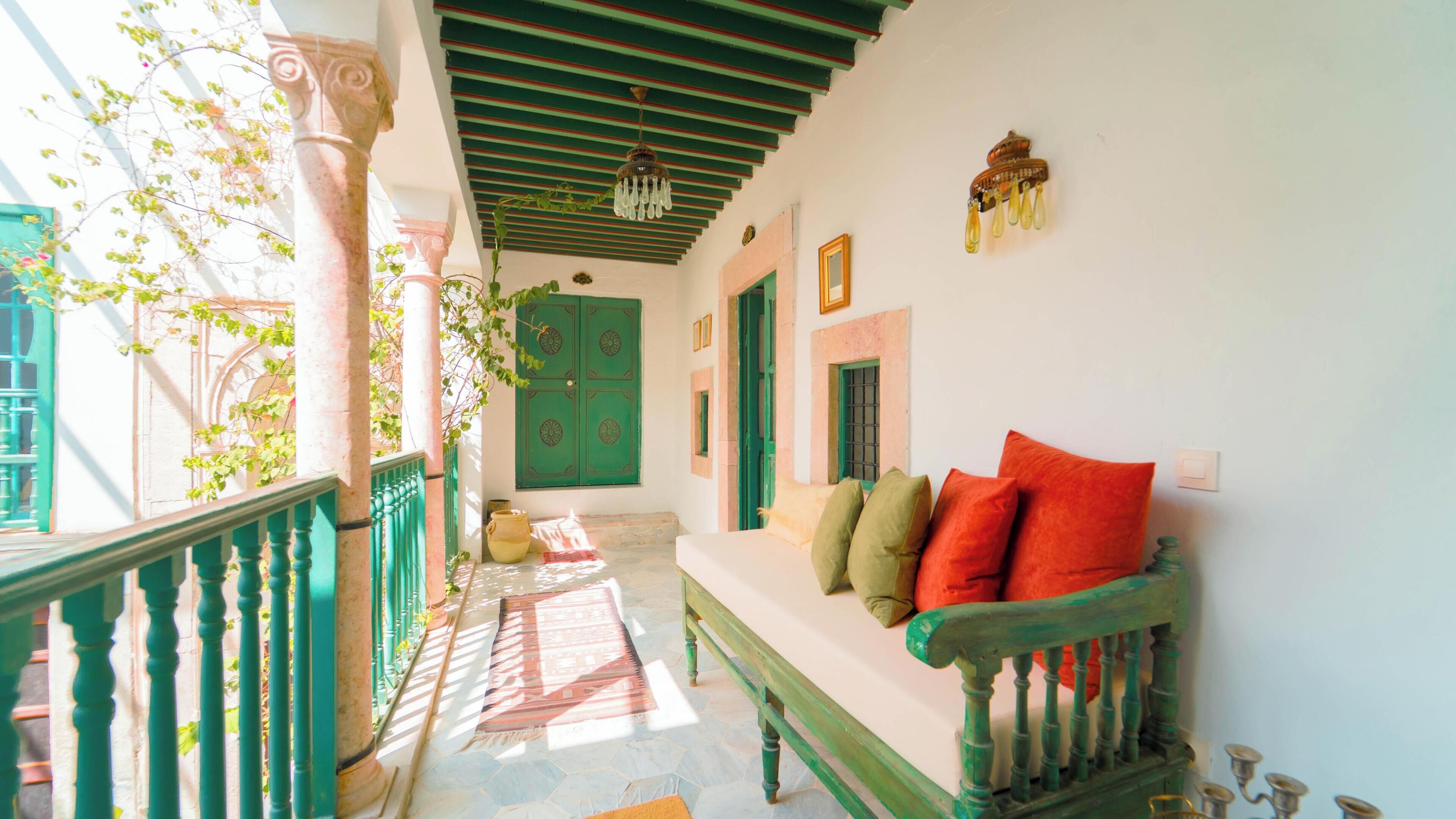 A cozy porch with a green bench and a tiled floor.