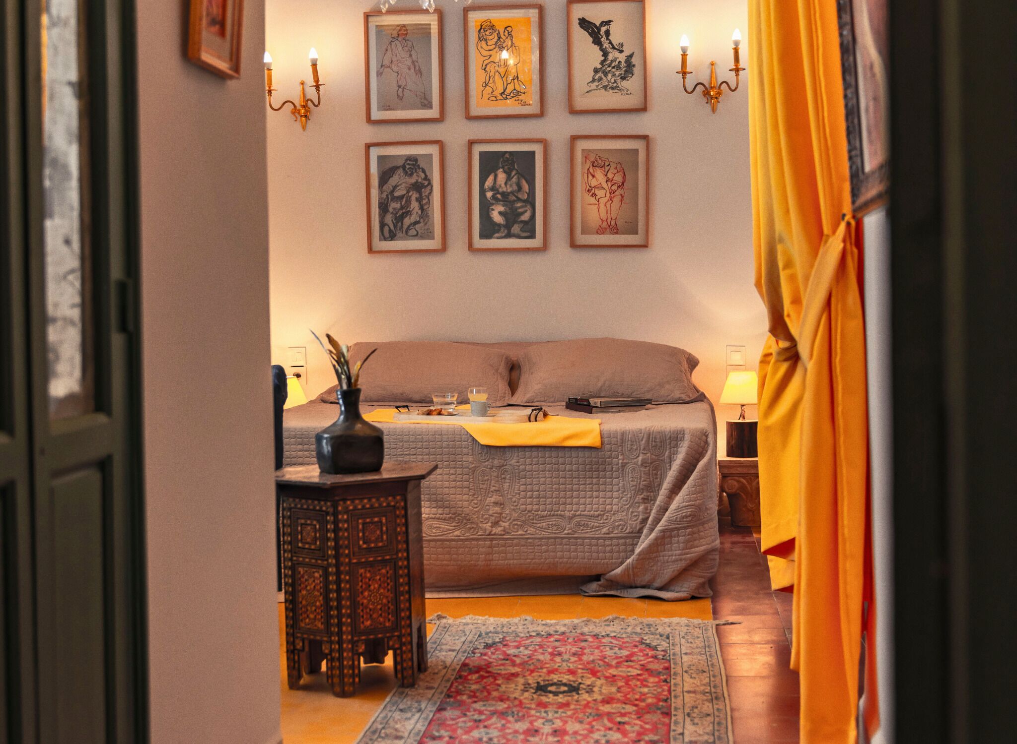Un dormitorio con cama, mesitas de noche, un florero y cuadros en la pared.