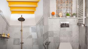 A bathroom with a shower, toilet, and a shelf with toiletries.