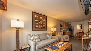 A living room with a sofa, two armchairs, a coffee table, and a fireplace. - Suites at Silver Tree: A212 One Bedroom Standard View (Oakland)
