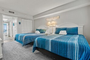 Una habitación de hotel con dos camas, un baño y un pasillo.