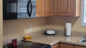 A kitchen with wooden cabinets, a black oven, a microwave, and a sink.