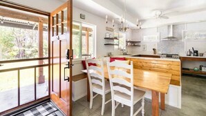 A modern kitchen with a wooden dining table and chairs, a built-in island, and a large window. - Cozy Volcano Room 🌋 (Volcano)