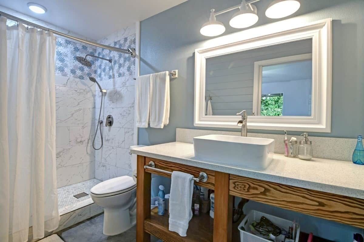 A bathroom with a shower, toilet, vanity with a mirror, and a sink.