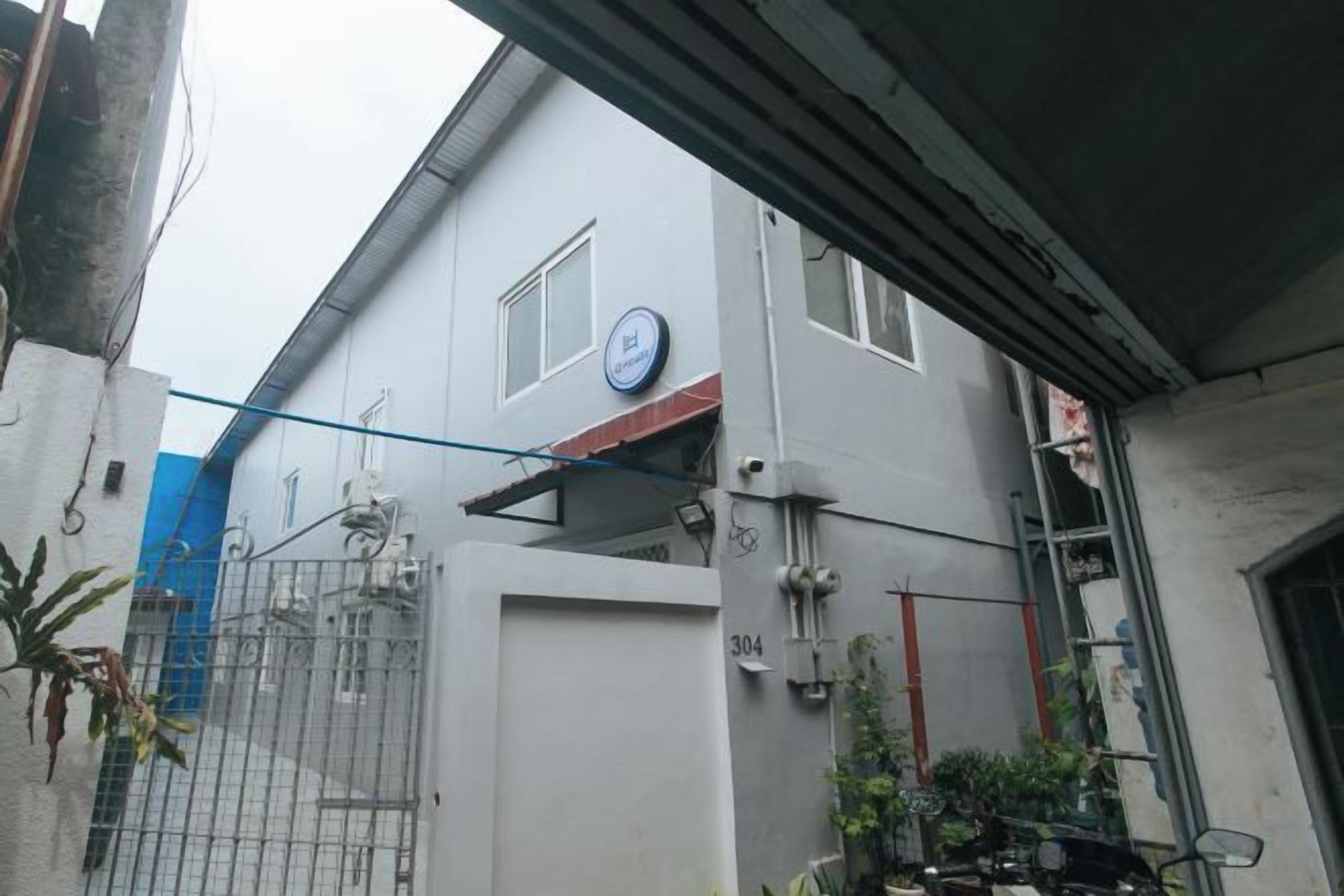 A building with a gated entrance, a visible number '304', and a blue circular sign on the wall.