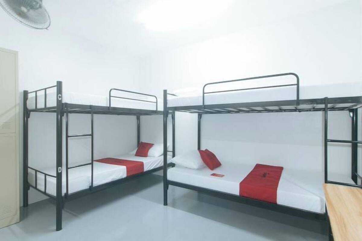 Un dormitorio con literas, un ventilador y un banco de madera.