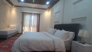 A bedroom with a bed, a nightstand, a lamp, a window with curtains, and a patterned rug. - TAMRILUXE HOUSE (Tamri)