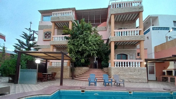 A two-story building with a swimming pool, outdoor seating, and a covered patio area. - TAMRILUXE HOUSE (Tamri)