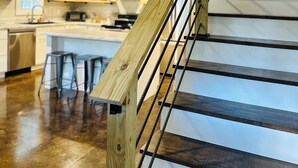 Een houten trap met metalen leuningen die naar een balkon op de tweede verdieping leidt.