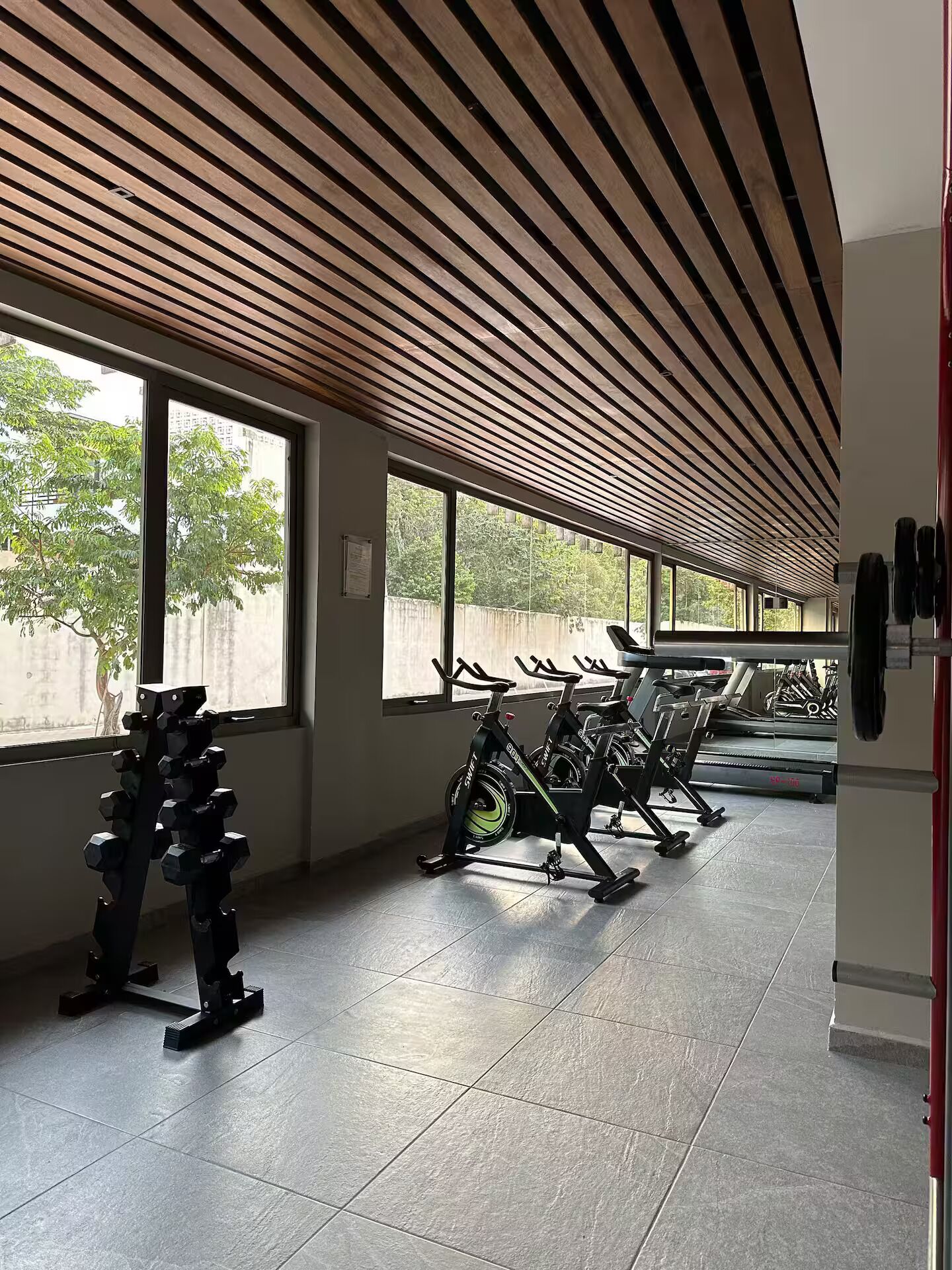 Un gimnasio con equipo de ejercicio, ventanas amplias y techo inclinado.