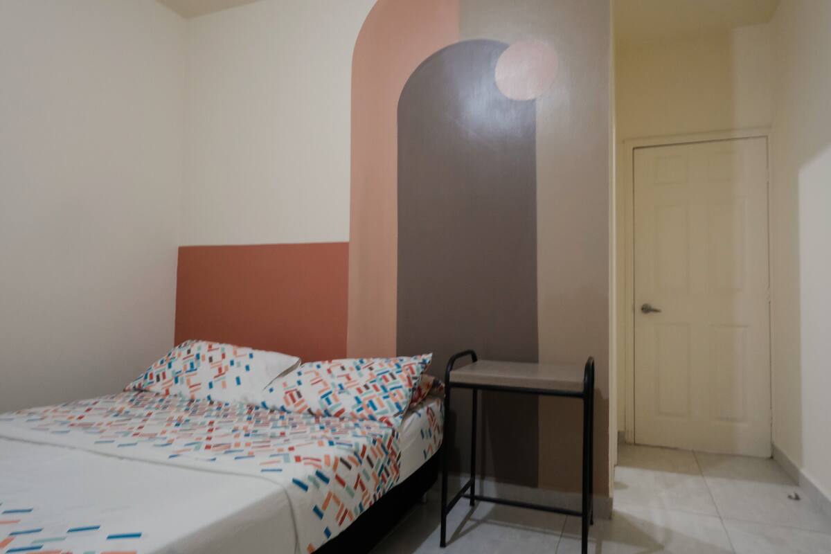 A bedroom with a bed, a small table, and a door.