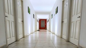 A long, narrow hallway with white doors on both sides, leading to a red door at the end. - Casa Colibri Palomino (Palomino)