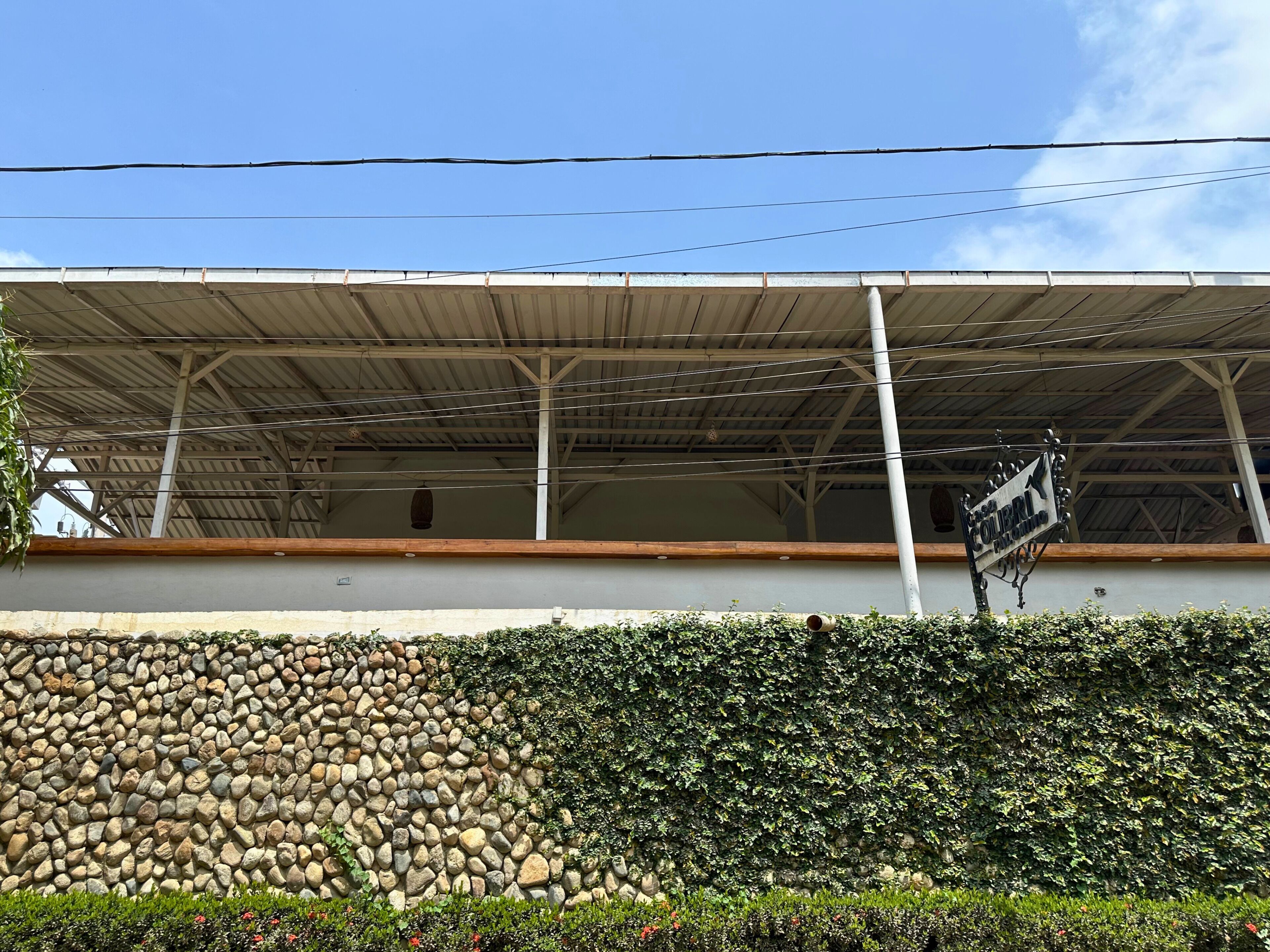 A building with a stone wall and a metal roof structure.