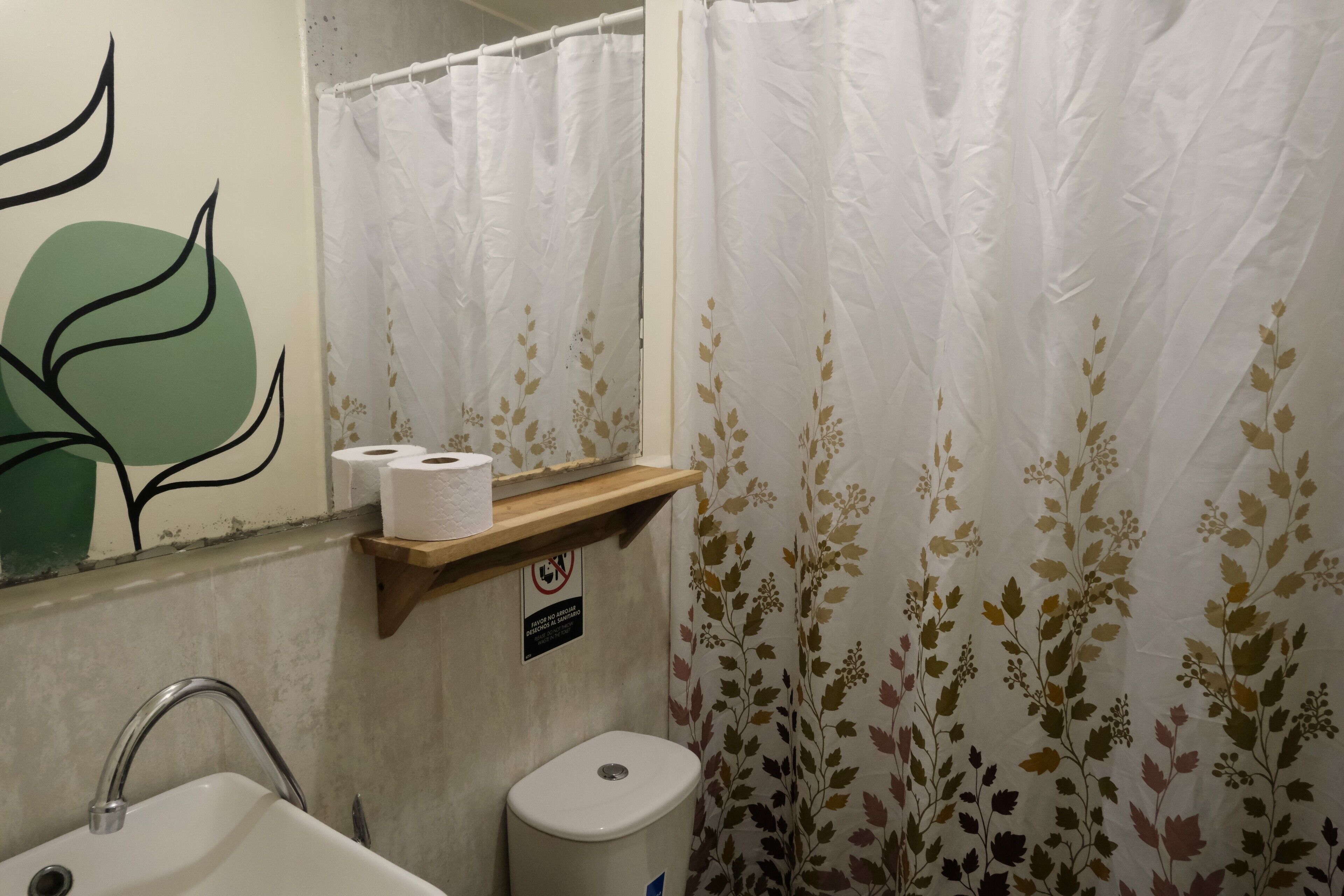A bathroom with a sink, toilet, and shower curtain with a floral pattern.