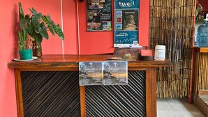 A reception desk with a poster advertising detox and wellness retreats, a fan, and a bamboo screen. - Casa Colibri Palomino (Palomino)