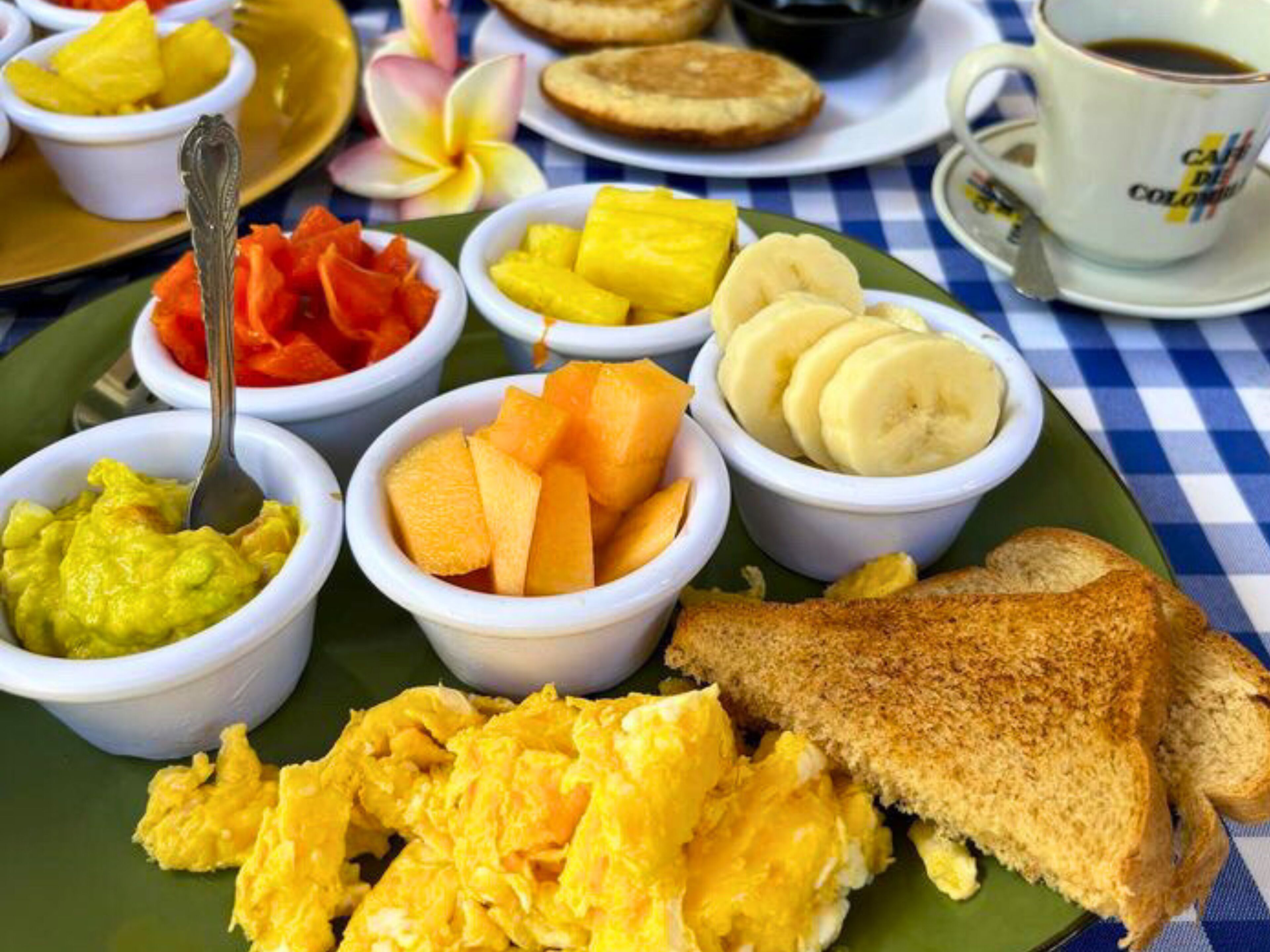 A breakfast plate with scrambled eggs, toast, and various fruits.