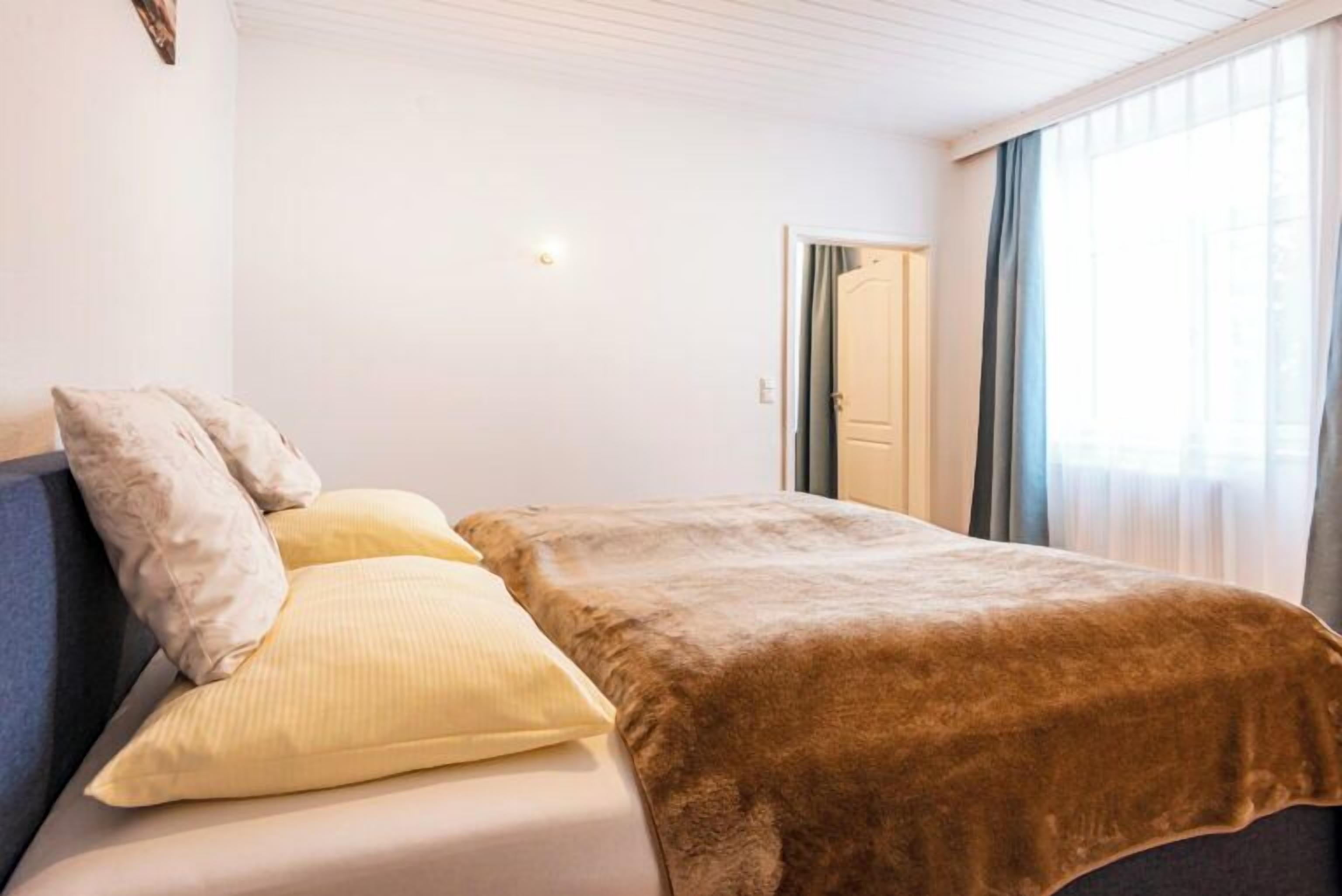 A bedroom with a bed, pillows, and a window with curtains.