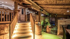 A wooden staircase leading to a bar area with wooden barrels and a rustic interior. - Hotel Bristol (Bad Gastein)