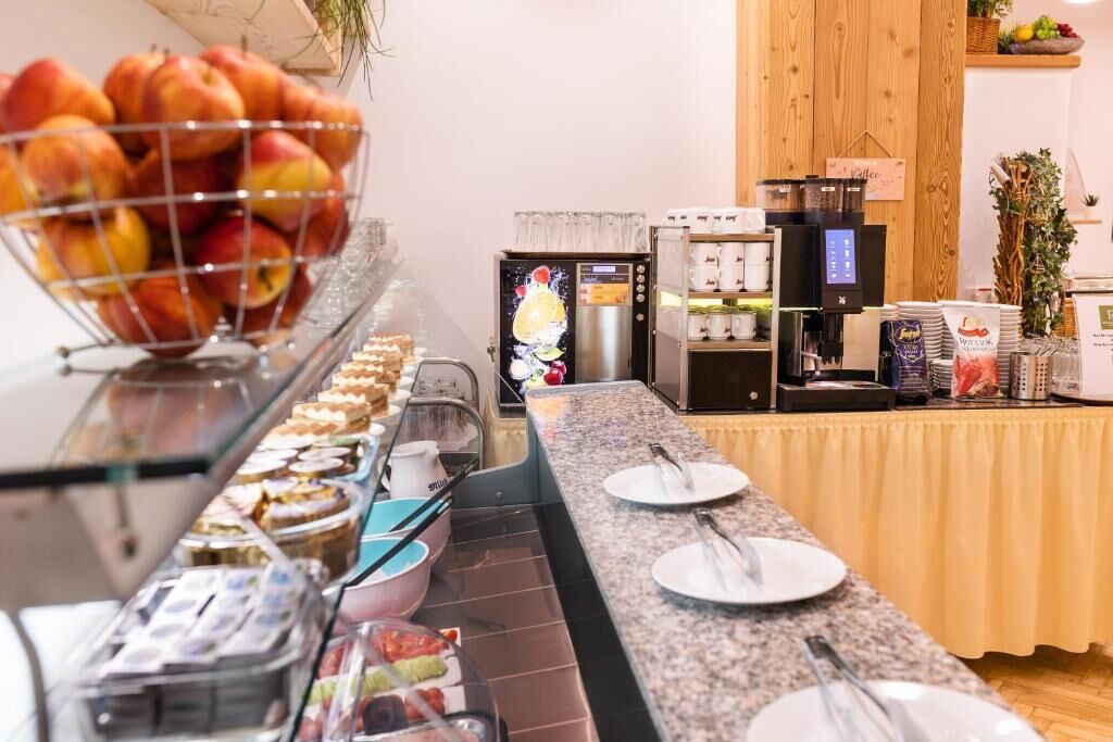 A buffet area with a variety of food items, including fruits and pastries, and a coffee station with multiple coffee machines.