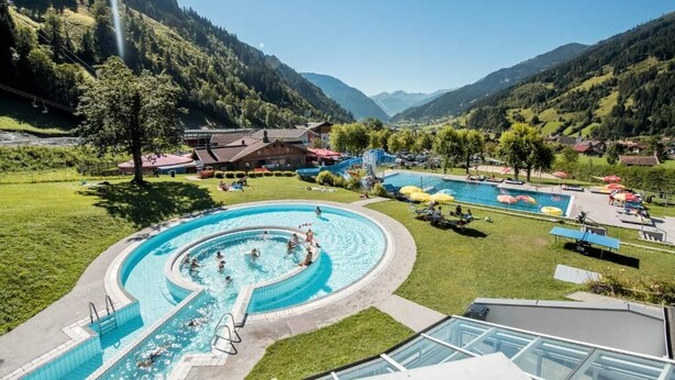 A resort with a large swimming pool, a mountain backdrop, and a view of the valley. - Hotel Bristol (Bad Gastein)