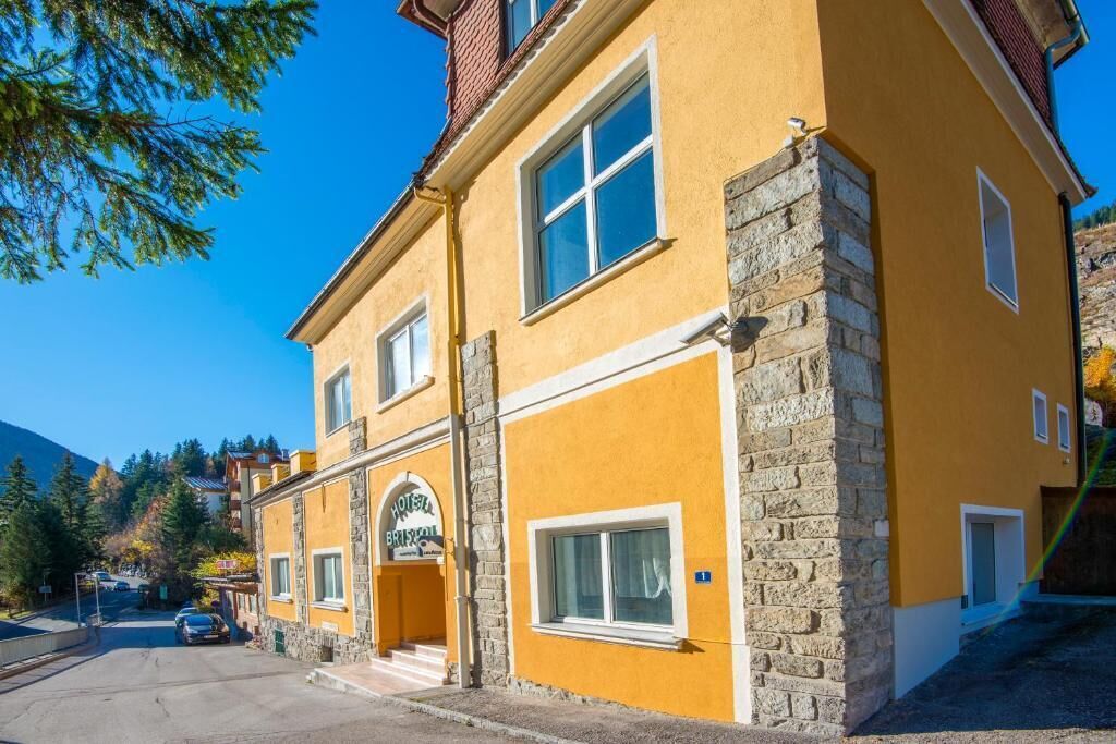Un hotel de dos pisos con fachada amarilla y detalles de piedra, que cuenta con una entrada destacada y un letrero.