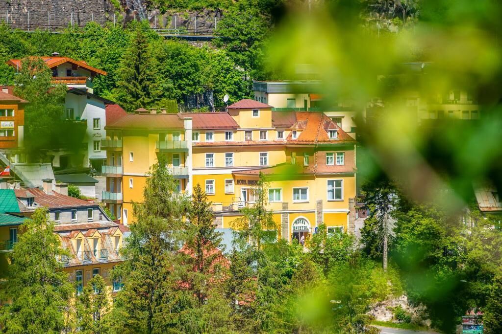 A multi-story hotel with balconies, surrounded by lush greenery.