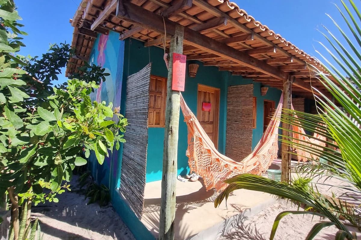 Une maison traditionnelle avec un hamac, une porte en bois et un mur bleu.