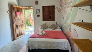 A bedroom with a bed, pillows, a red blanket, a wooden door, and a window. - Hospedaria Flor do Xandó (Porto Seguro)