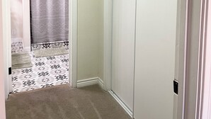 A narrow hallway with a carpeted floor, a patterned rug, a white door, and a closet with a sliding door. - Center of Vegas - 5 beds house with heated pool (Las Vegas)