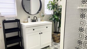 A bathroom with a white vanity, black towel rack, round mirror, and a potted plant. - Center of Vegas - 5 beds house with heated pool (Las Vegas)