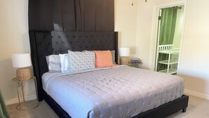 A bedroom with a large bed, dark headboard, two bedside tables with lamps, a green curtain, and a white door. - Center of Vegas - 5 beds house with heated pool (Las Vegas)