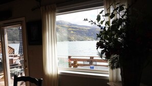 A room with a large window overlooking a lake and mountains, a wooden chair, and a potted plant. - Magic on Lake San Cristobal  - Northshore #9 -  Quiet End Unit with Great Views (Lake City)