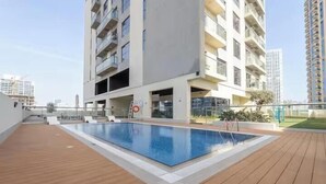 A modern apartment building with a rooftop pool, balconies, and a clear sky. - Vogue | Jeewar By Badr JVC near Circle Mall (Dubai)
