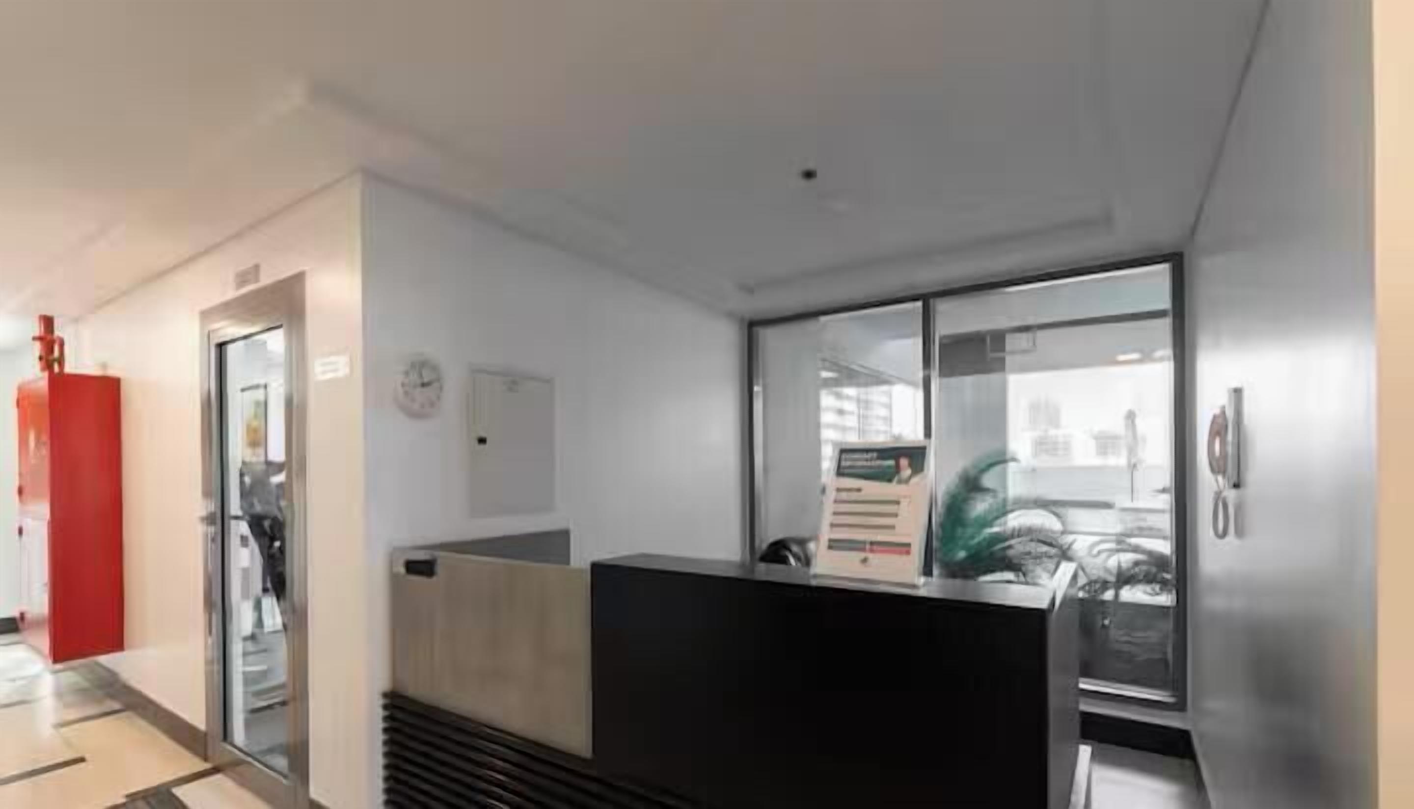 A reception area with a reception desk, a clock, and a window with a view of the city.