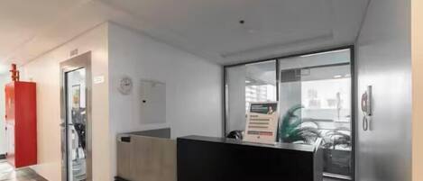 A reception area with a reception desk, a clock, and a window with a view of the city.