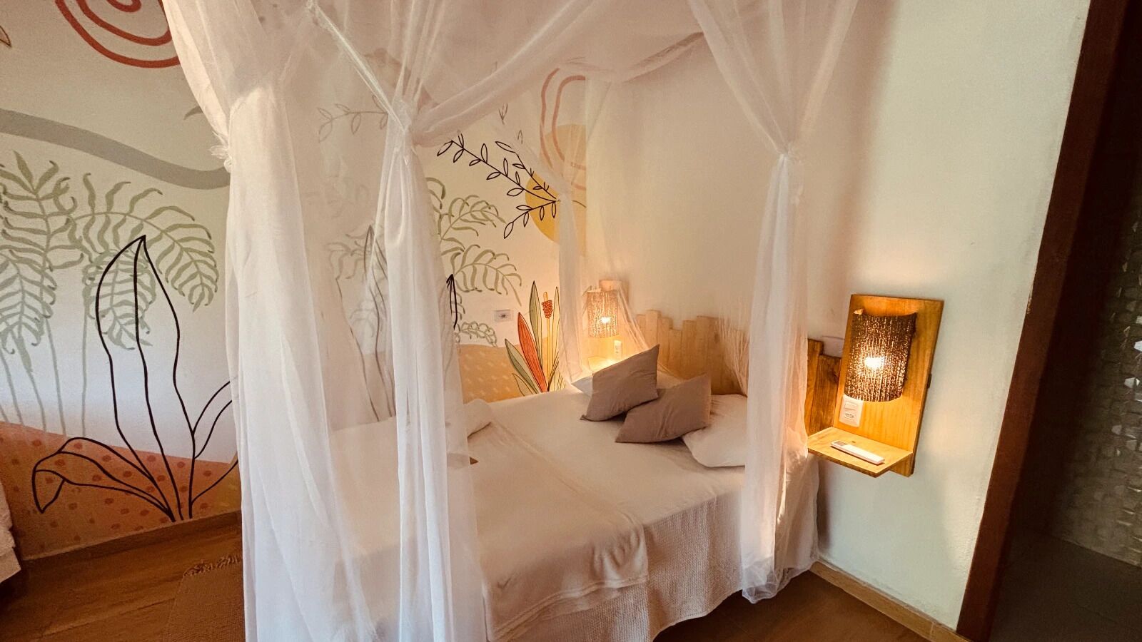 A bedroom with a canopy bed, a bedside table with a lamp, and a wall-mounted light fixture.