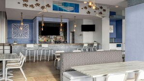 Eine moderne Bar mit Theke, Sitzgelegenheiten und dekorativen Wandbildern.