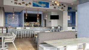 Un área de bar moderna con mostrador, asientos y decoración mural.