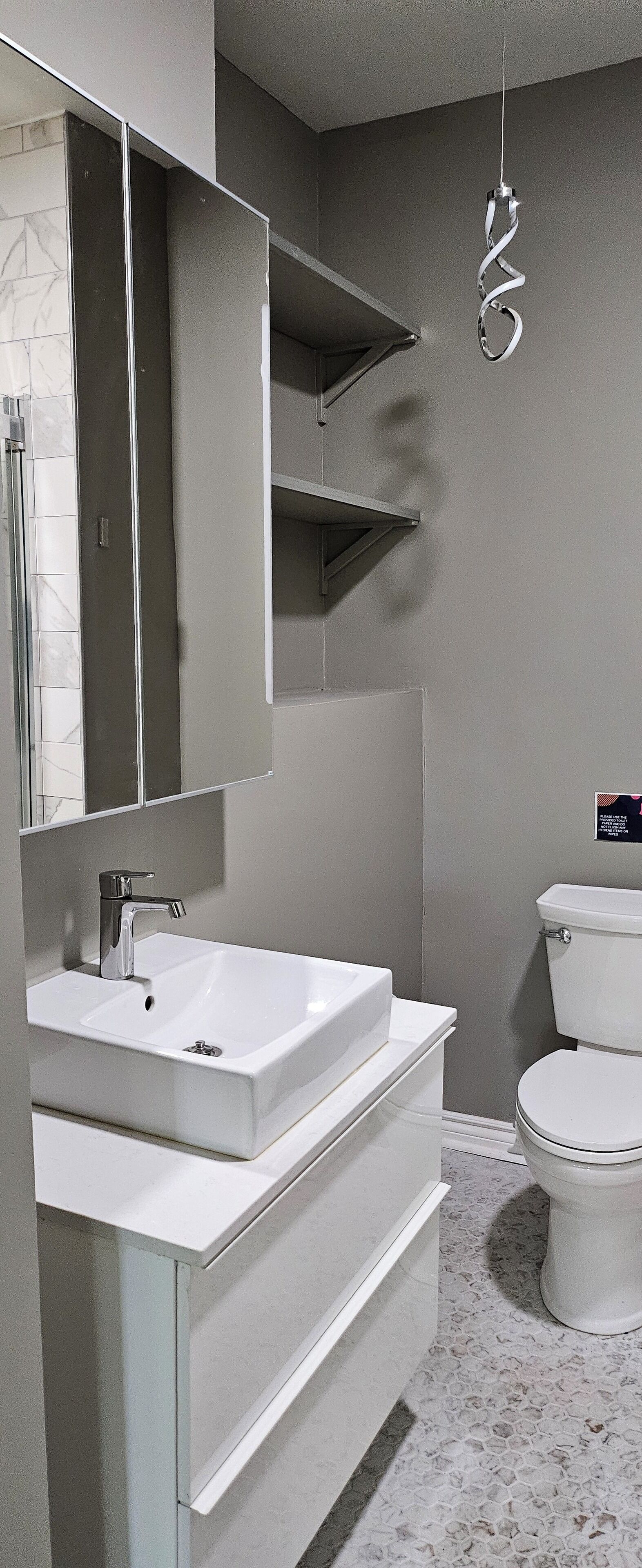 Moderni kylpyhuone, jossa on valkoinen pesuallas, peili ja wc-istuin.