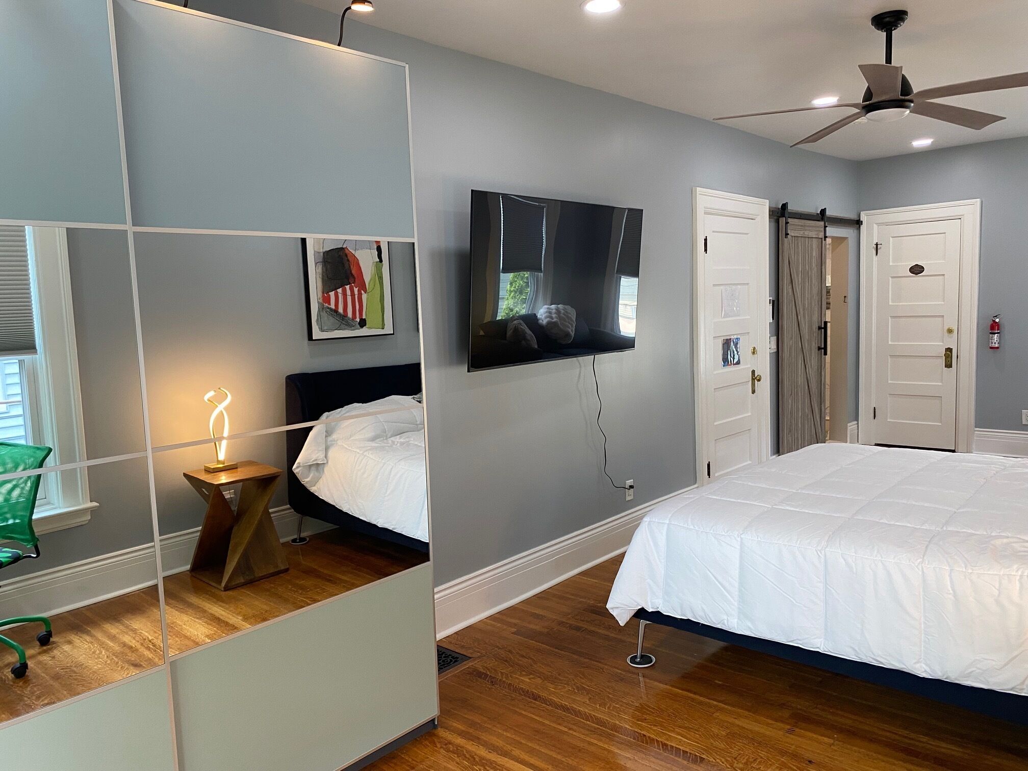 A modern bedroom with a bed, a TV, and a ceiling fan.