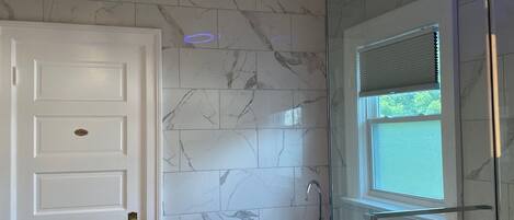 A modern bathroom with a freestanding bathtub, a glass-enclosed shower, and a white door.