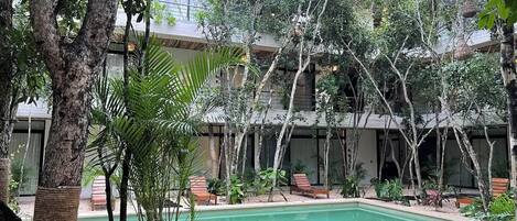 Une piscine entourée d’arbres et un bâtiment doté de nombreux balcons.