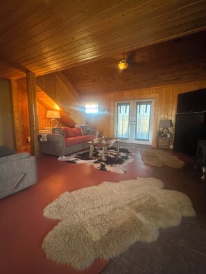 Una habitación acogedora con paredes de madera, un sofá, una mesita de centro y una chimenea.