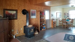 Ein Holzinnenraum mit Kamin, Essbereich und Regalen mit unterschiedlichen Gegenständen.