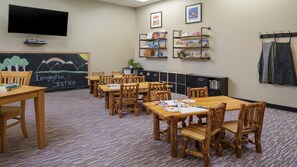A classroom with wooden tables and chairs, a chalkboard with artwork, shelves with books and supplies, and a television mounted on the wall. - Mountain Getaway: Studio with Kitchen & Fireplace at Vail (Vail)