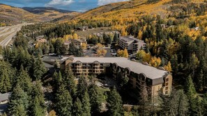 A multi-story hotel with a central courtyard, surrounded by dense forest and autumn foliage. - Mountain Getaway: Studio with Kitchen & Fireplace at Vail (Vail)