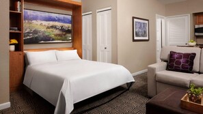 A hotel room with a large bed, a sofa, a coffee table, a painting on the wall, and a bookshelf. - Mountain Getaway: Studio with Kitchen & Fireplace at Vail (Vail)