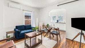 Una sala moderna con un sofá azul, una mesa de centro de madera y un televisor sobre un mueble.