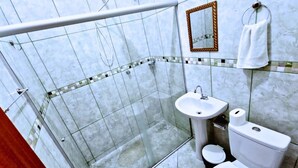 A bathroom with a glass shower enclosure, a sink, a toilet, and a mirror. - Pousada Bela Rainha (Aparecida)